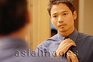 Asia Images Group - Young man adjusting tie, looking in mirror