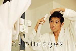 Asia Images Group - Young man blow drying hair, looking in mirror