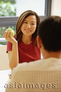 Asia Images Group - Couple facing each other, woman holding an apple