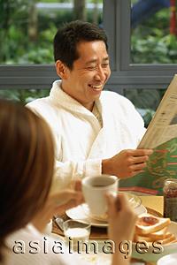 Asia Images Group - Couple at breakfast table, man reading newspaper