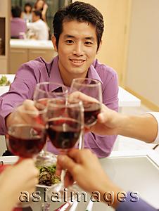 Asia Images Group - Friends toasting wine glasses across dinner table, over the shoulder view