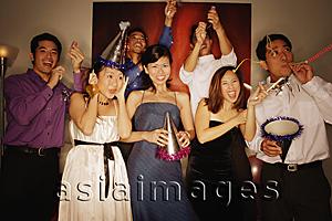 Asia Images Group - Group of friends having a party at home, playing with streamers and noisemakers