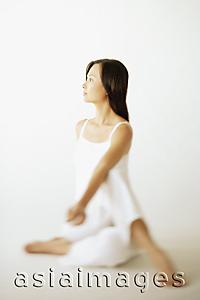 Asia Images Group - Young woman sitting on floor, looking away