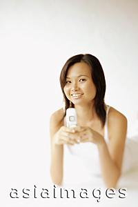 Asia Images Group - Young woman lying on floor, holding mobile phone