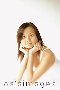 Asia Images Group - Young woman lying on floor, hands on chin, looking at camera