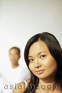 Asia Images Group - Young woman looking at camera, man behind her