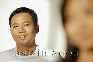 Asia Images Group - Young man looking at camera, woman in front of him