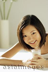 Asia Images Group - Young woman lying on front, holding glass of milk