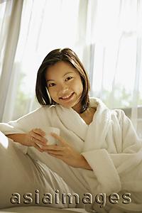 Asia Images Group - Young woman holding coffee cup, looking at camera