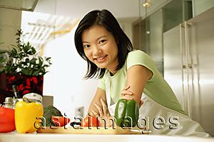 Asia Images Group - Young woman leaning on kitchen counter, looking at camera