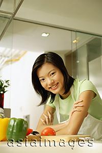 Asia Images Group - Young woman leaning on kitchen counter, arms crossed