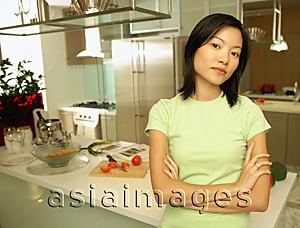 Asia Images Group - Young woman leaning on kitchen counter, looking at camera