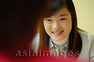 Asia Images Group - Young woman at a cafe, another young woman in front of her