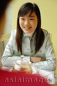 Asia Images Group - Young woman sitting opposite another person, smiling