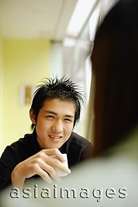 Asia Images Group - Young man holding teacup, facing young woman
