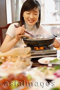 Asia Images Group - Young woman eating at Chinese restaurant.