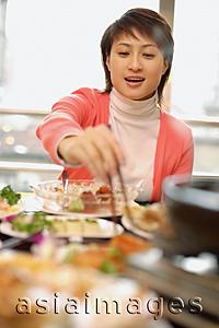 Asia Images Group - Young woman at a Chinese restaurant, eating