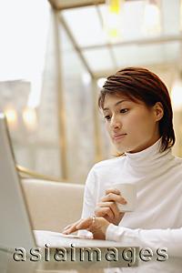 Asia Images Group - Young woman wearing white turtleneck, using laptop