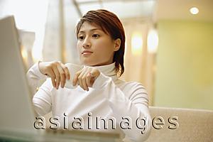 Asia Images Group - Young woman wearing white turtleneck, using laptop