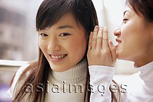 Asia Images Group - Young woman whispering to another woman