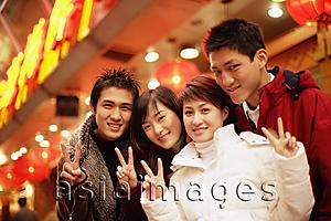Asia Images Group - Friends looking at camera, smiling, making peace signs