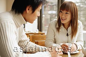 Asia Images Group - Young adults at a cafe, talking, side by side