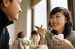 Asia Images Group - Couple at a Chinese restaurant, eating with chopsticks