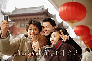 Asia Images Group - Couples looking at camera phone, making peace signs