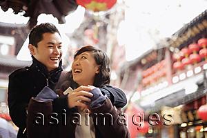 Asia Images Group - Young man embracing young woman, urban scene