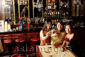 Asia Images Group - Three women holding wine glasses, looking at camera