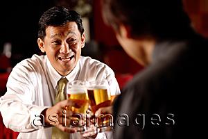 Asia Images Group - Two men toasting with beer glasses.