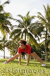 Asia Images Group -  Man doing stretching exercises in park, bending forward