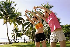 Asia Images Group - Women doing stretching exercises in park, bending sideways