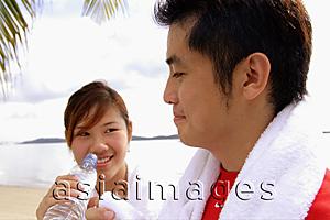 Asia Images Group - Couple at beach, woman holding water bottle, man holding towel