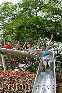 Asia Images Group - Group of young people sliding down playground slide