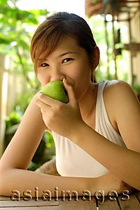 Asia Images Group - Woman eating apple, looking at camera