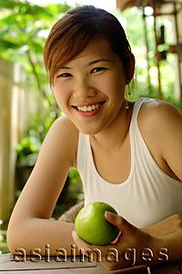 Asia Images Group - Woman holding an apple, looking at camera