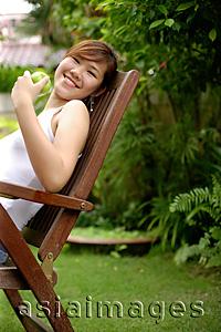 Asia Images Group - Young woman sitting on chair, outdoors.