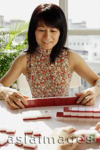Asia Images Group - Woman looking at mahjong tiles