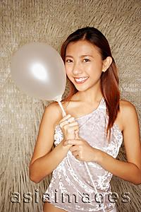 Asia Images Group - Young woman holding balloon, looking at camera