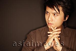 Asia Images Group - Young man, hands clasped, looking away, portrait