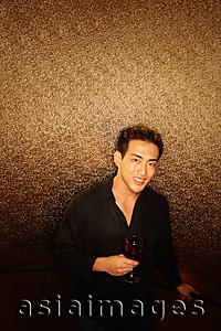 Asia Images Group - Young man, holding wine glass, looking at camera