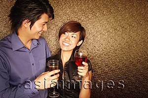 Asia Images Group - Couple holding drinks, looking at each other
