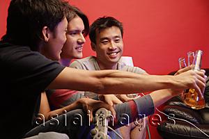 Asia Images Group - Young men toasting with beer bottles
