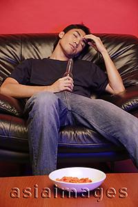 Asia Images Group - Young man on soda, holding beer bottle, eyes closed