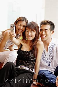 Asia Images Group - Two young women and one young man looking at camera phone