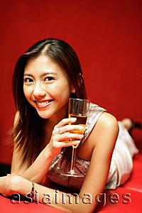 Asia Images Group - Young woman with champagne glass, smiling at camera