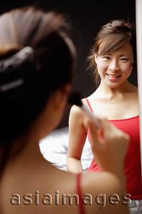 Asia Images Group - Young woman applying blusher, looking at mirror