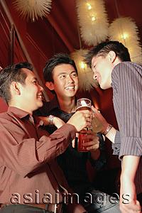 Asia Images Group - Young men in night club toasting with drinks