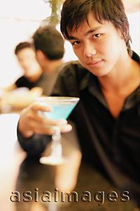 Asia Images Group - Young man at bar counter holding cocktail glass